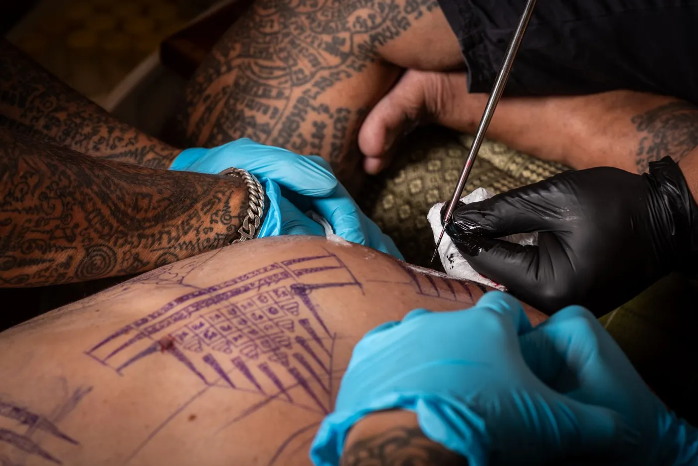 The master hand-poking a Sak Yant with a traditional needle